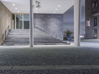 the sidewalk in front of the building is empty of people or building and stairs are illuminated