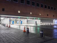 people walking through the rain on the sidewalk in a parking garage at night with lights on