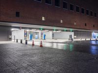 people walking through the rain on the sidewalk in a parking garage at night with lights on