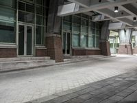 an empty sidewalk with no people outside of it, near the building's entrance