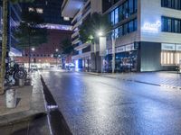 empty street with tall buildings in a city at night near two cyclists in the rain