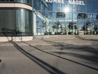 the glass windows have many designs on them and are reflecting the outside of it on the sidewalk