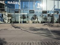 the glass windows have many designs on them and are reflecting the outside of it on the sidewalk
