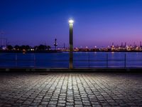 an empty bench sitting by the water with the view of the industrial landscape behind it