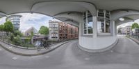 a fisheye photograph of buildings and a river with water in it and a bike rider at the side