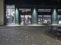 a street corner with two chairs and one empty bench in the middle of it at night