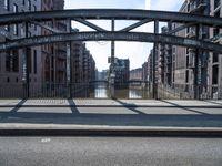 the shadow of the man is shown on a street bridge over the canal, and he looks on