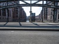 the shadow of the man is shown on a street bridge over the canal, and he looks on