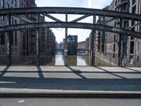 the shadow of the man is shown on a street bridge over the canal, and he looks on