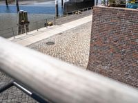 a brick wall with a brick walkway near a water front with people walking past it