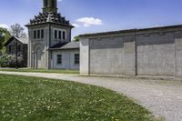 an old church is next to a wall and grassy field with daisies, in the country