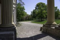 a walkway that is next to some large columns and trees in the background on a sunny day