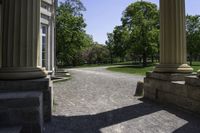 a walkway that is next to some large columns and trees in the background on a sunny day