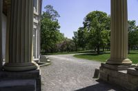 a walkway that is next to some large columns and trees in the background on a sunny day