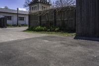 a large white clock tower standing next to a wood fence and walled in area