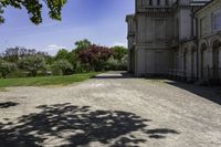 a long gravel driveway with a clock tower in the distance, and trees in the foreground