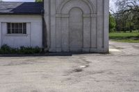 an empty parking lot in front of a building with a big stone doorway that has a door that is painted blue