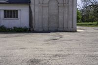 an empty parking lot in front of a building with a big stone doorway that has a door that is painted blue