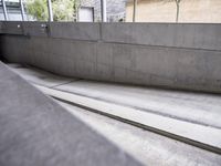 a skateboarder is in a concrete parking garage space riding down a road and looking at the ground