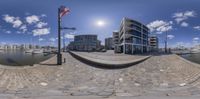 a fish eye lens shows the reflection of the buildings and boats in the harbor area