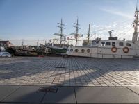 the large white ship is parked in front of the harbor boat dock next to the tall sailboat