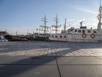 the large white ship is parked in front of the harbor boat dock next to the tall sailboat