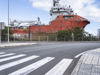 a ship on the water with a road passing by it and street sign behind it