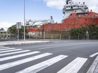 a ship on the water with a road passing by it and street sign behind it