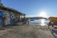 a boat is sitting near a small wooden shed and pier on a sunny day at a harbor