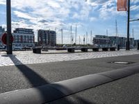 an empty bench next to a harbor with some boats on it and buildings in the background