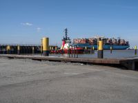 a harbor with cargo trucks parked beside it and one being unloaded by a boat