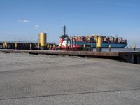 a harbor with cargo trucks parked beside it and one being unloaded by a boat