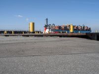 a harbor with cargo trucks parked beside it and one being unloaded by a boat