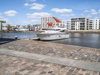 a harbor next to the water with a yacht in it and the docks are lined by brick pavers