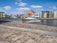 a harbor next to the water with a yacht in it and the docks are lined by brick pavers