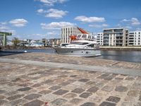 a harbor next to the water with a yacht in it and the docks are lined by brick pavers