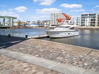 a harbor next to the water with a yacht in it and the docks are lined by brick pavers