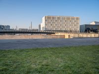 this grass field has been cut short to cover the area in the distance, and it is a grassy area next to an old building