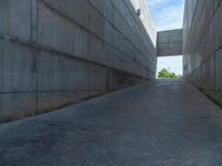 the empty parking lot in front of a wall with apartment buildings on it and a skateboarder on a ramp