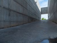 the empty parking lot in front of a wall with apartment buildings on it and a skateboarder on a ramp