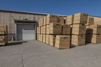 the stacks of lumber are stacked to the side of the building next to pallets of other wood