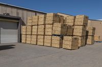 stacked piles of wooden blocks outside a storage room with blue sky above them and a truck in front