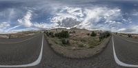 two roads and sky filled with clouds above them in the middle of an image with a wide lens