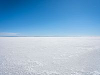 footprints are in the sand on the shore of a lake or water, making the shape of a heart