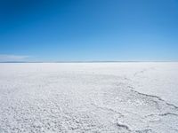 footprints are in the sand on the shore of a lake or water, making the shape of a heart