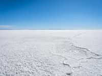 footprints are in the sand on the shore of a lake or water, making the shape of a heart