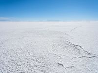 footprints are in the sand on the shore of a lake or water, making the shape of a heart