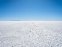 footprints are in the sand on the shore of a lake or water, making the shape of a heart