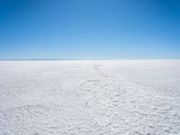 footprints are in the sand on the shore of a lake or water, making the shape of a heart