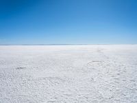 footprints are in the sand on the shore of a lake or water, making the shape of a heart